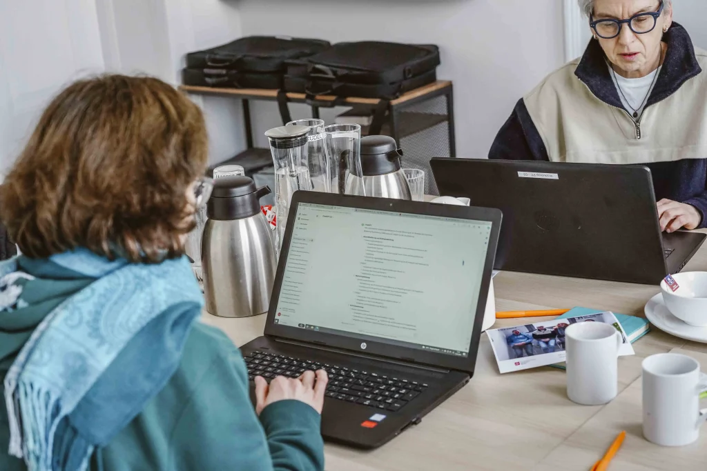 2 Mitarbeitende probieren KI-Tools am Laptop aus